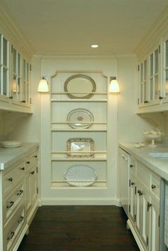 a kitchen with white cabinets and plates on the shelves