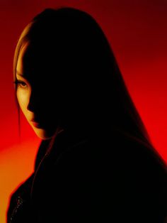 a woman with long hair standing in front of a red background