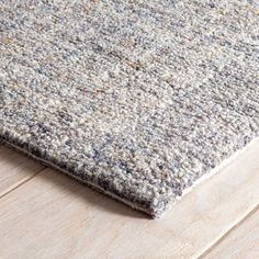 an area rug on top of a wooden floor with white and gray carpeting in the background