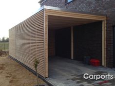 a wooden garage with the door open on a brick building that is being built in front of it