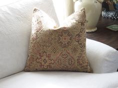 a white couch with a decorative pillow on it's back and two vases in the background