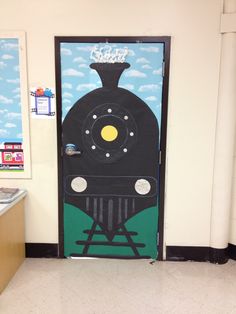 a door with a train painted on it in a school hallway next to a desk