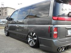 the rear end of a gray van parked in a parking lot