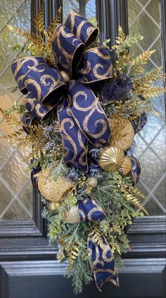 a blue and gold christmas wreath hanging on a door