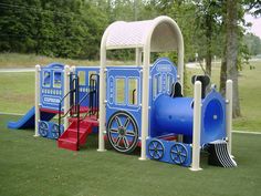 a children's play area with a blue train and red steps on the grass