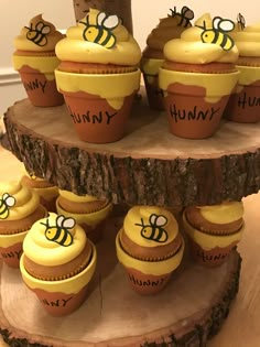 cupcakes with yellow frosting and bees on them sitting on a tree stump