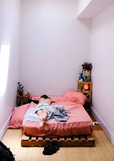 a person laying on top of a bed in a bedroom next to a wooden floor