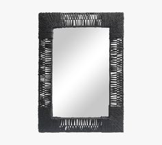 a mirror that is on top of a white wall and has black fringe trim around the edges