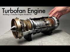 a person is touching an engine model on a table with the words turboflan engine behind it