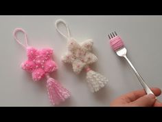 someone is holding a fork and two small crocheted ornaments next to each other