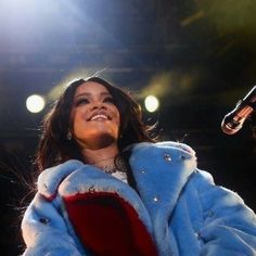 a woman in a blue coat standing next to a microphone