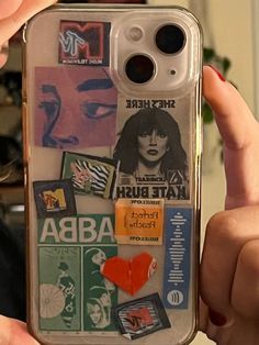 a person holding up a cell phone case with stickers on it and various pictures