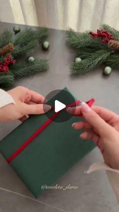 two hands opening a green gift box with red ribbon