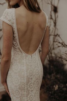 the back of a woman's wedding dress with an open back and beaded details