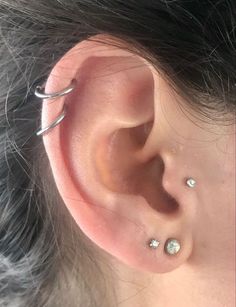 a woman's ear with three piercings on the top and bottom of it