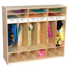 a wooden cubby with several coats and umbrellas on the top shelf in front of it