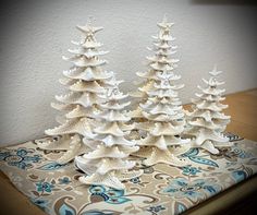 three white ceramic christmas trees sitting on top of a table