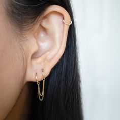 a close up of a person wearing a pair of ear piercings with chains attached to them