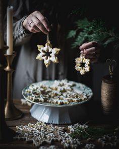 a person is decorating some cookies on a cake platter with candles in the background