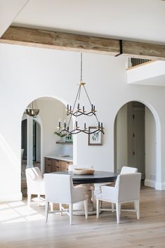 a dining room table with white chairs and a chandelier hanging from the ceiling