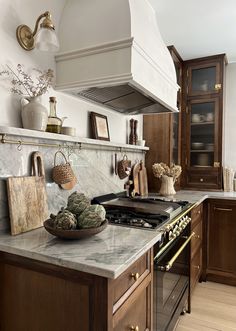 a kitchen with marble counter tops and wooden cabinetry, along with an oven hood