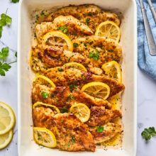 a casserole dish with chicken and lemons on the side next to two forks