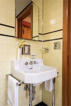 a white sink sitting under a bathroom mirror next to a towel dispenser