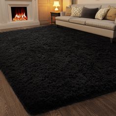 a living room with a couch, fireplace and black rug in front of the fire place