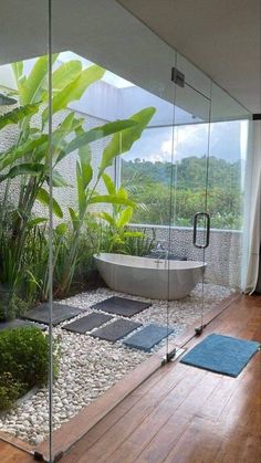 a bathroom with glass walls and wooden flooring next to a bathtub in the middle