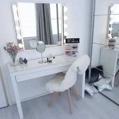 a white desk with a mirror, stool and lights on it in a room filled with furniture