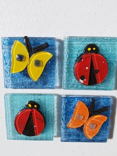 four glass magnets with ladybug, butterfly and leaf designs on blue background