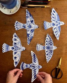 someone is cutting out some paper butterflies on a table with scissors and other crafting supplies