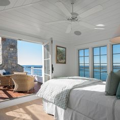 a bedroom with a bed and two windows overlooking the water