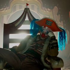 a creepy clown sitting on top of a wooden chair in front of a circus tent