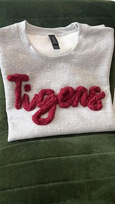 Get ready to cheer on your team in style with our personalized sports sweatshirt, featuring a custom monogram crafted with cozy chenille yarn. Perfect for proud sports moms and spirited fans, this top lets you flaunt your team pride in a unique and fashionable way. Choose from our soft, chunky chenille yarn for bold, standout lettering (limit to 7 letters for best results), or opt for a finer yarn for longer names. Each sweatshirt is handmade with care, so no two will be exactly alike. INFORMATI Game Day Cotton Sweatshirt With Embroidered Logo, Cotton Sweatshirt With Embroidered Logo For Game Day, Team Spirit Sweatshirt With Custom Embroidery For Game Day, Varsity Sweatshirt With Embroidered Logo For Fans, Sporty Cotton Sweatshirt With Custom Embroidery, Game Day Cotton Sweatshirt With Letter Embroidery, Game Day Cotton Sweatshirt With Custom Embroidery, Cotton Team Spirit Sweatshirt With Custom Embroidery, Sports Fan Cotton Sweatshirt With Embroidered Logo