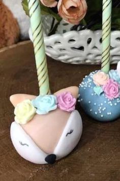 two small candles are sitting next to each other on a table with flowers in the background