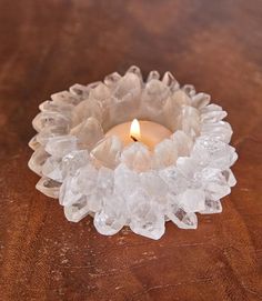 a candle that is sitting on a table with ice cubes around it and a lit candle in the middle