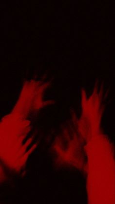 two hands reaching towards each other with red light in the dark behind them on a black background