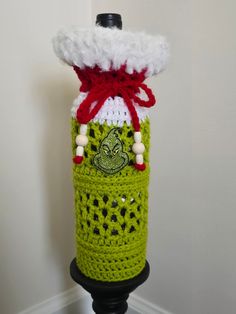 a crocheted green bottle with a red and white top