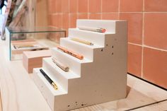 there are several different types of pens and pencils on this display case that is made out of concrete