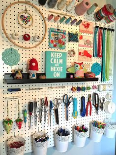 a peg board with scissors and other crafting supplies on it, hanging from the wall