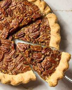 a pecan pie is cut into slices on a marble counter top with a serving utensil