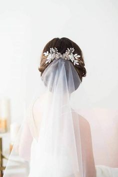 a woman wearing a veil with flowers on it's head and hair comb in her hair