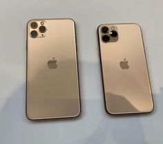 two gold iphones sitting side by side on top of a table next to each other