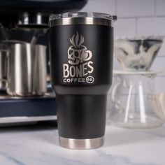 a stainless steel and black coffee cup sitting on top of a counter