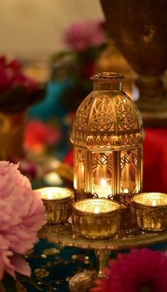 candles are lit on a tray with flowers in front of the candle holder and vases