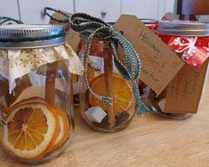 three mason jars filled with orange slices and cinnamon sticks, wrapped in twine string