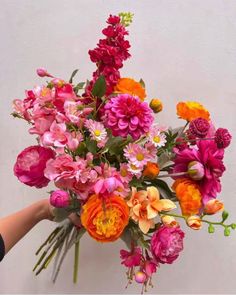 a person holding a bouquet of flowers in their hand with the other hand on it