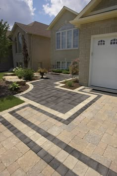 a driveway in front of a house with two garage doors on each side and landscaping around it