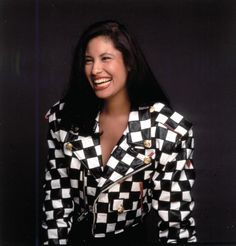 a woman in a black and white checkered jacket smiling